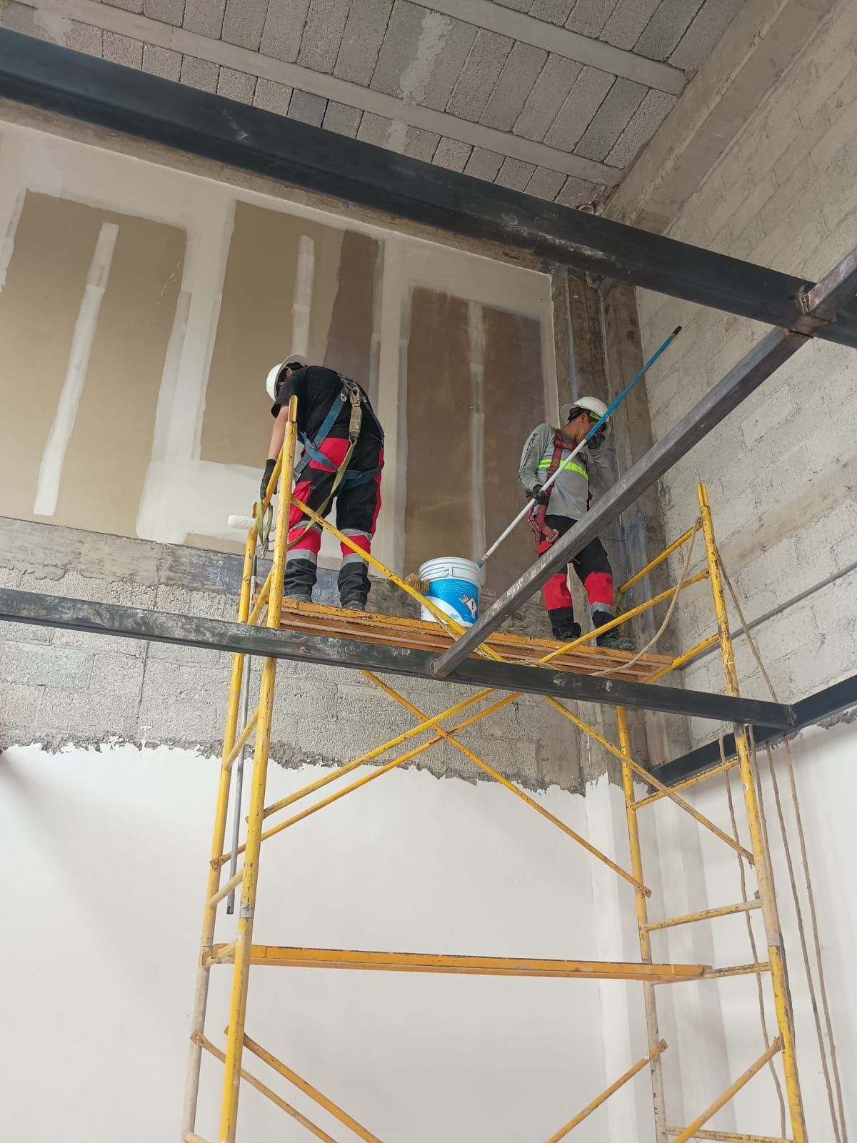 Personal de Grupo PERSA con equipo de seguridad y arnés sobre andamios realizando empastado y pintura