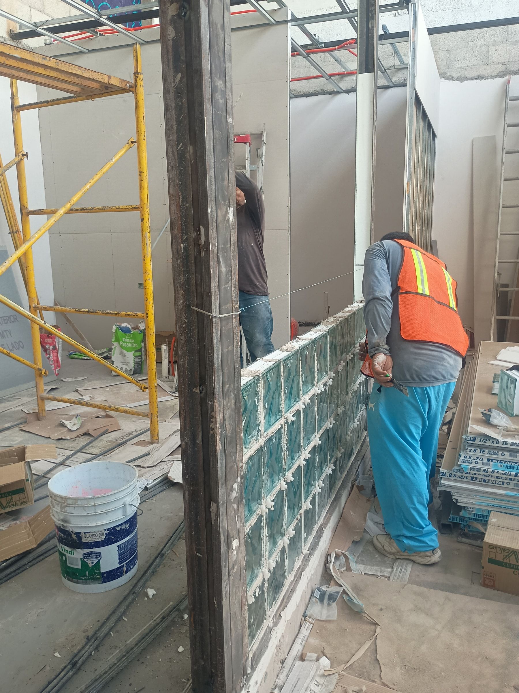 Colocación artesanal de muro de vitroblock con crucetas y alineación de acero